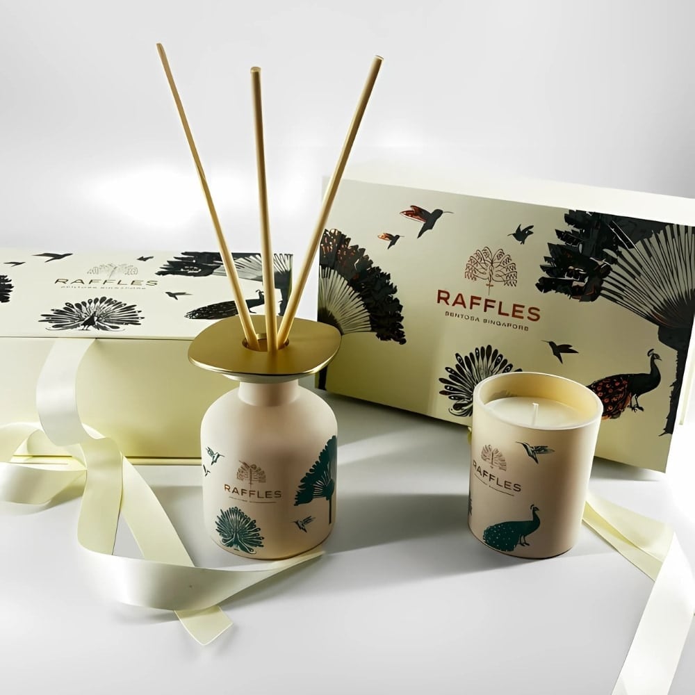 A Raffles candle and reed diffuser beside their printed gift boxes.